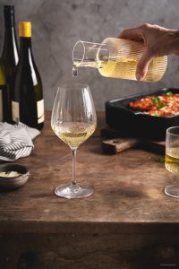 Vegetarischer-Brotauflauf - Wein wird in ein Glas geschenkt